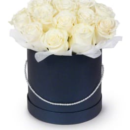 White roses arranged in a black round hat box