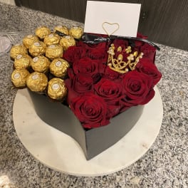 Heart-shaped box of red roses and gold-wrapped chocolates with a card.