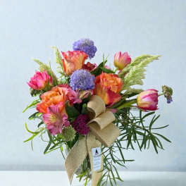 Bouquet of pink and orange roses with purple blooms in a glass vase