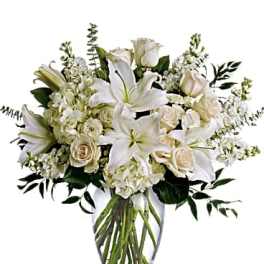 White lilies and cream roses in a clear glass vase