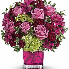 Pink and burgundy rose bouquet in a magenta glass vase