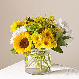 Bouquet of yellow and white flowers in a clear glass vase