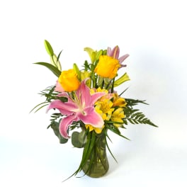 Pink lilies and yellow roses in a glass vase