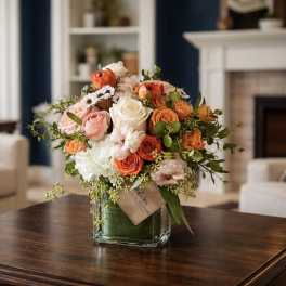Bouquet of orange, pink, and white roses in a glass vase