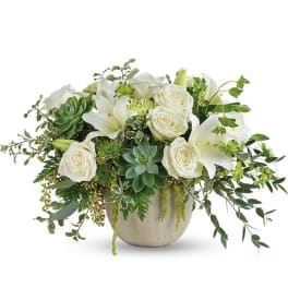 White roses and lilies arranged in a round vase with green succulents