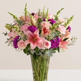 Pink lilies and roses in a clear glass vase