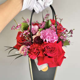 Handheld floral gift bag with red and pink roses and carnations