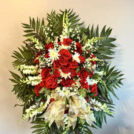 Standing floral spray with red roses and white flowers on a gold ribboned easel