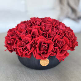 Round arrangement of red roses in a black vase