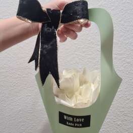 White flower bouquet in pale green wrap with a black bow