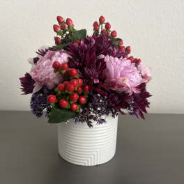 Pink and purple floral arrangement in a white ribbed vase