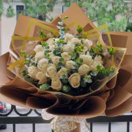 Bouquet of white roses wrapped in brown paper with a ribbon