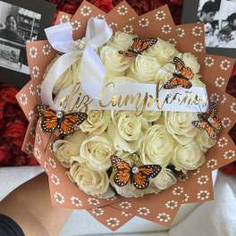 Cream rose bouquet with butterfly decorations and a white ribbon