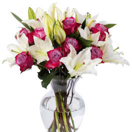 Arrangement of white lilies and bright pink roses in a clear glass vase