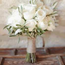 White rose bouquet with green foliage wrapped in burlap