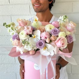 Large pastel bouquet of roses, ranunculus, and orchids in a pink box