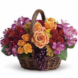 Basket of peach roses and purple flowers with grapes