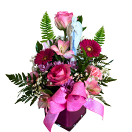 Pink mixed flower arrangement with a small angel figurine in a vase