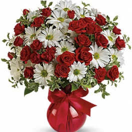 Bouquet of red roses and white daisies in a red vase with a ribbon