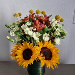 Sunflowers, alstroemeria, and white carnations in a glass vase