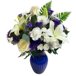 White lilies and roses with purple accents in a blue vase