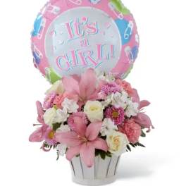 Pink and white flower arrangement in a white pot with an "It’s a Girl" balloon
