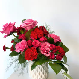 Pink and red roses with carnations in a white vase