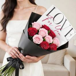 Woman holding a bouquet of pink and red roses wrapped in black paper