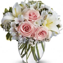 Pink roses and white lilies in a clear glass vase