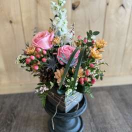 Pink roses and mixed flowers arranged in a dark vase