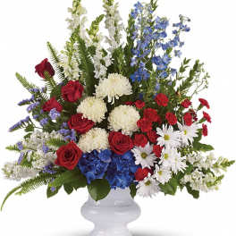 Tall red, white, and blue flower arrangement in a white pedestal vase