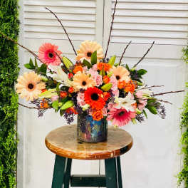 Colorful mixed bouquet in a patterned vase with gerbera daisies and roses