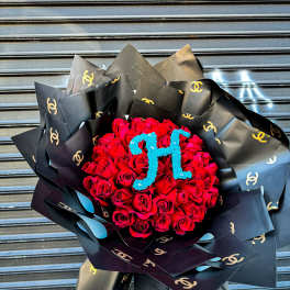 Large bouquet of red roses with blue monogram, wrapped in black logo paper