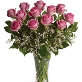 Pink roses arranged in a clear glass vase with white filler flowers