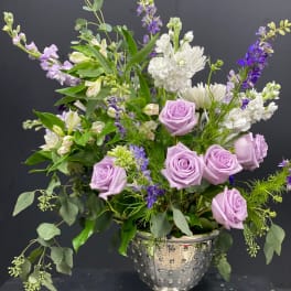 Lavender roses and white flowers in a silver pedestal vase