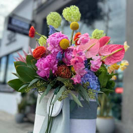 Colorful mixed bouquet in a wrapped hatbox with pink anthuriums and hydrangeas