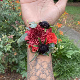 Small wrist corsage with red and dark burgundy flowers