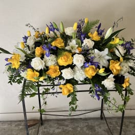 Large floral spray with yellow and white roses and purple blooms on a stand