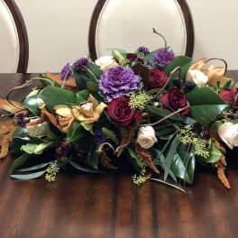 Low floral centerpiece with red, white, and purple blooms on a dining table