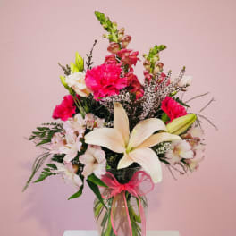 Bouquet of lilies, pink carnations, and snapdragons in a glass vase