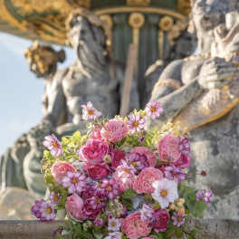Pink bouquet of roses and daisy-like flowers on a stone ledge