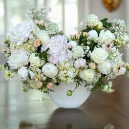 White and blush floral arrangement in a white bowl vase