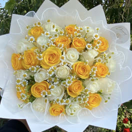 Bouquet of yellow and white roses with small daisy flowers wrapped in white paper