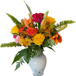 Colorful bouquet of roses, lilies, and daisies in a white vase