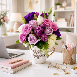Pink and purple roses in a white mug on a desk