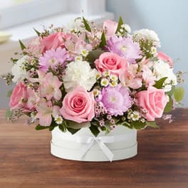 Pink and white mixed flower arrangement in a round white box with ribbon