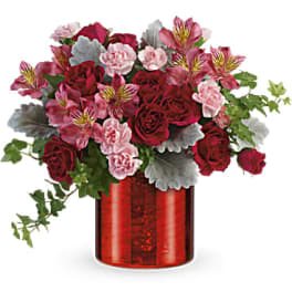 Red roses and pink flowers in a red glass vase