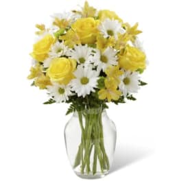 Yellow roses and white daisies in a clear glass vase