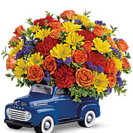 Bouquet of mixed flowers arranged in a blue pickup truck container