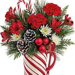 Christmas bouquet in a candy cane mug with red flowers and pinecones